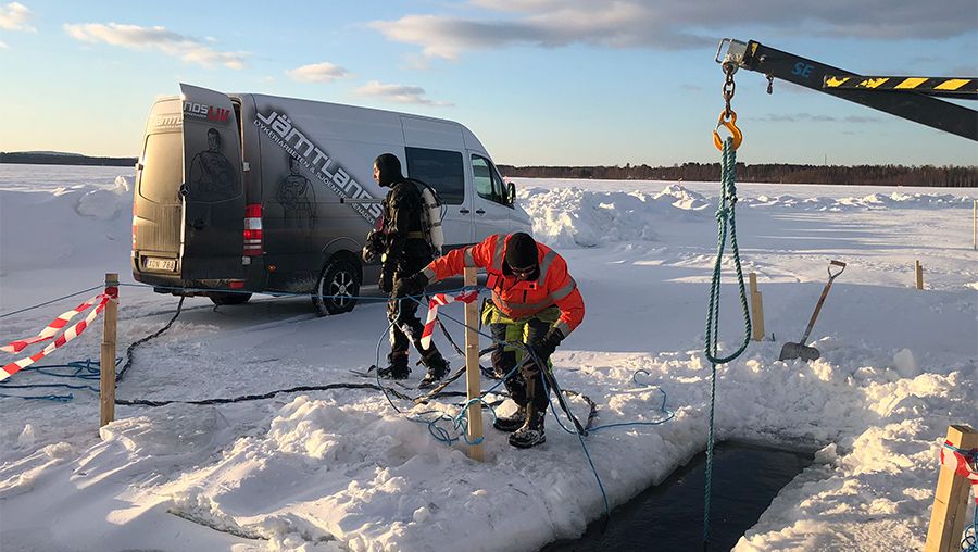 Två killar som jobbar med vinterförläggning och issågning